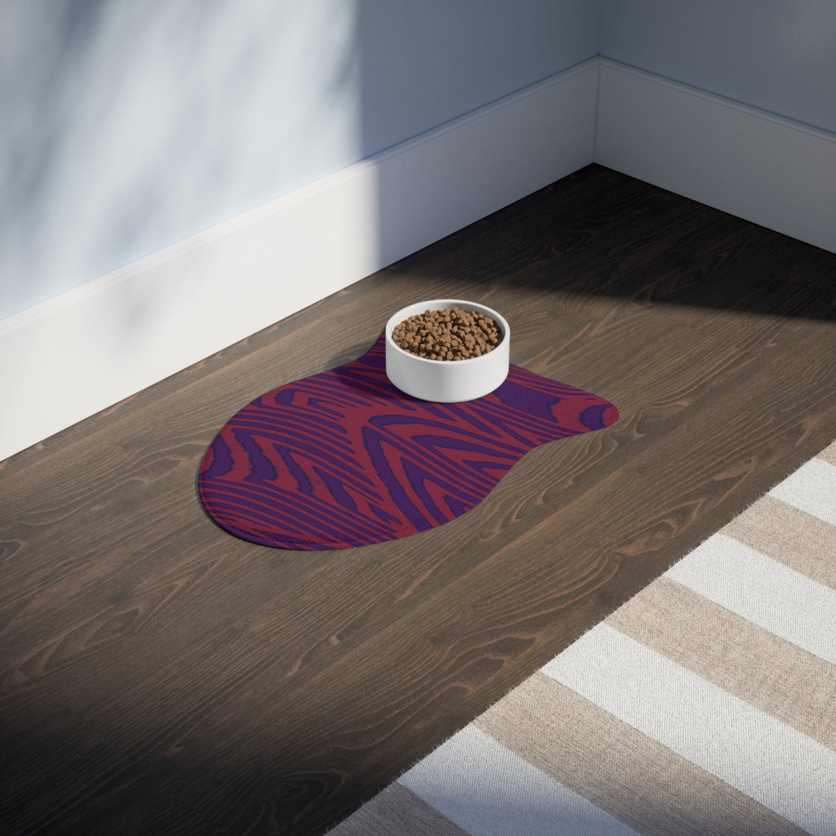 The beautifully styled Pet Feeding Mat resting on the floor, showcasing a striking purple and red wood grain design. This memory foam dog mat adds both flair and functionality as a non-slip mat for feeding pets. It's a versatile option for pet owners seeking a washable mat that blends seamlessly into any contemporary home.