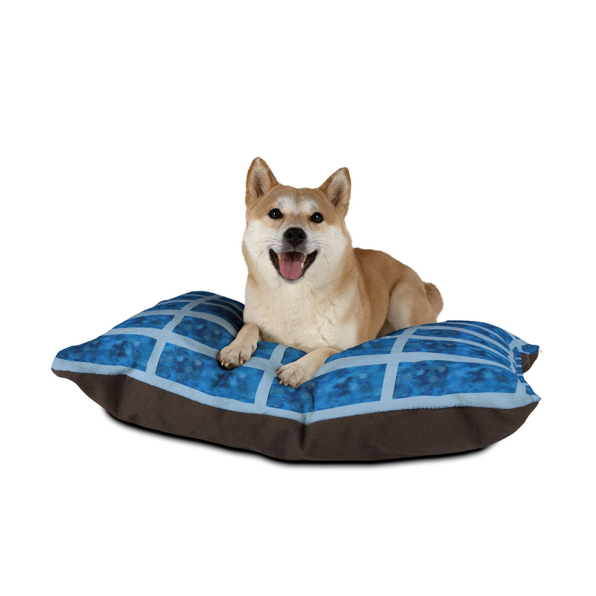 Happy Shiba Inu lying on the Blue Grid Plush Pet Bed by Printify, illustrating the comfort and style of this waterproof dog bed in a playful setting.