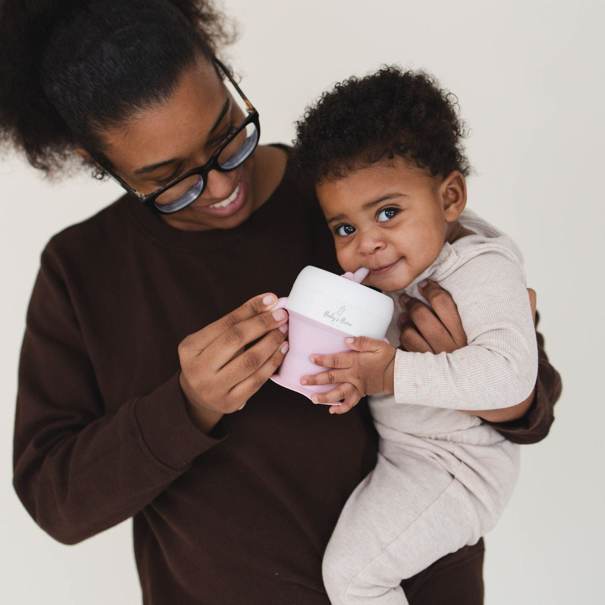 Parent feeding a baby with the Bite Size Bundle Baby's Brew toddler feeding set snack cup
