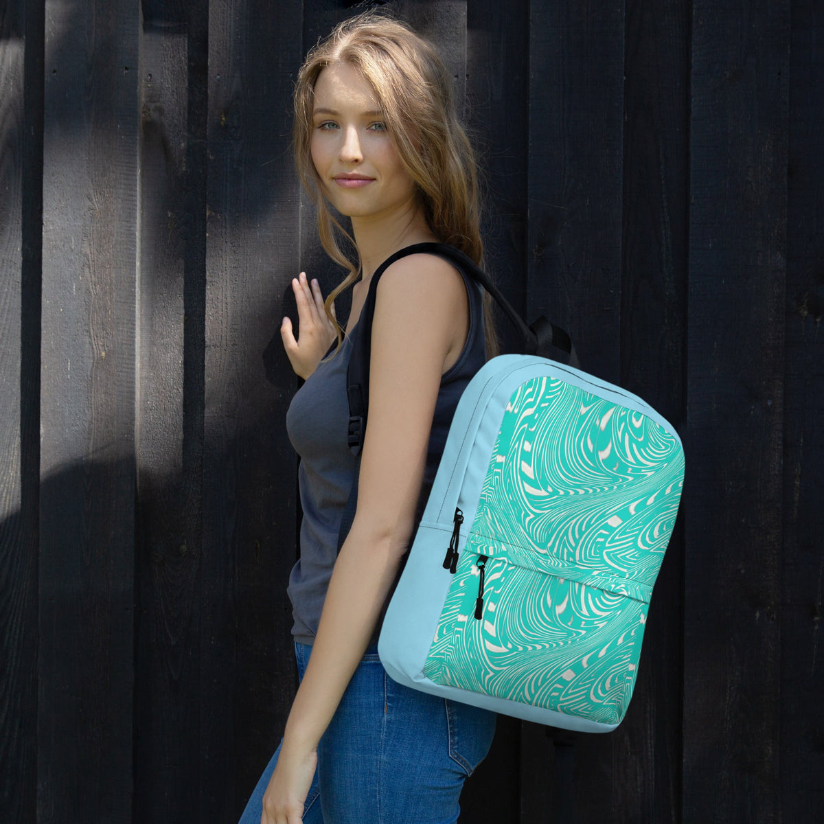 Stylish medium-sized water-resistant backpack perfect for back to school with a built-in apple laptop holder, featuring a colorful swirl design, worn by a young woman against a rustic wooden background.