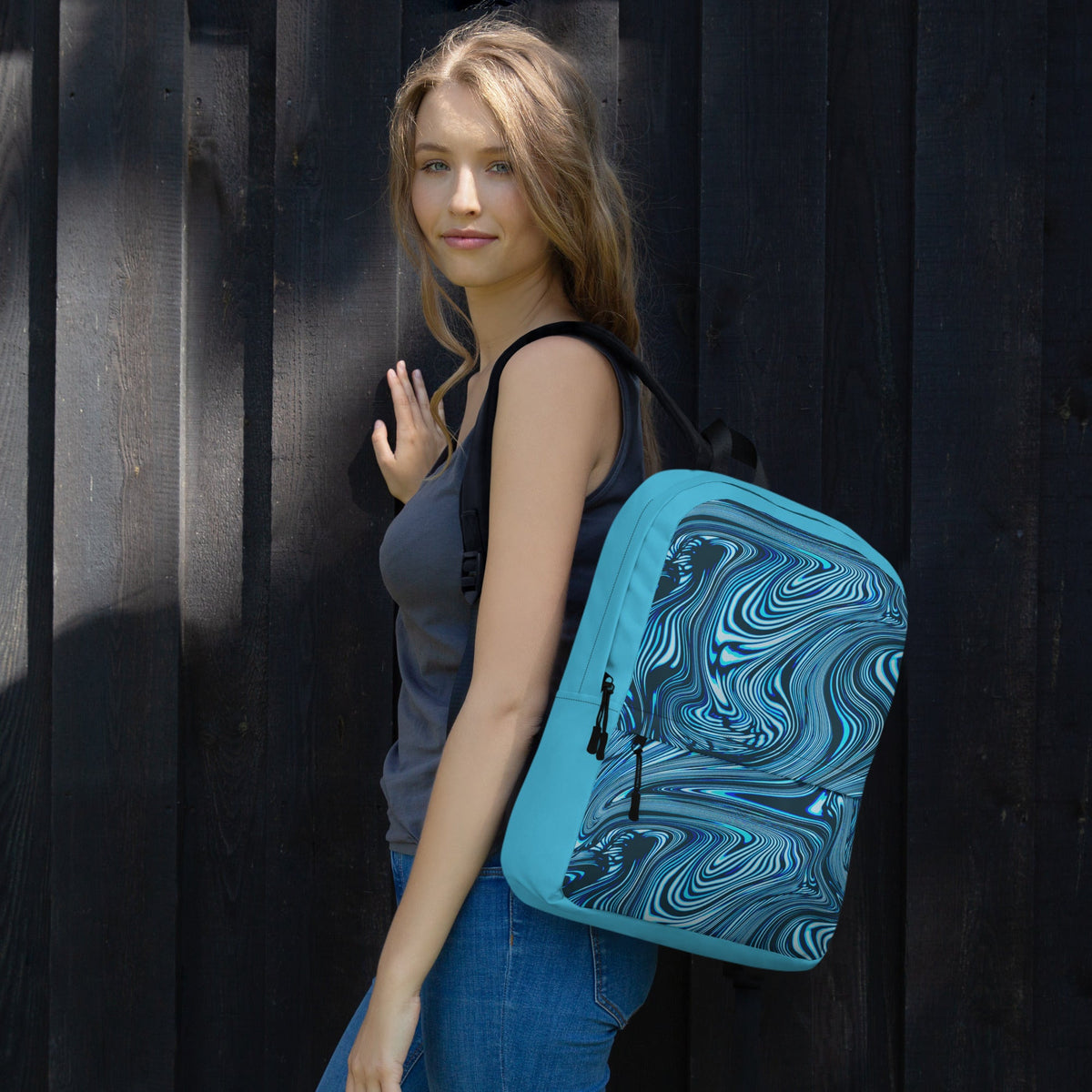 Stylish medium size backpack perfect for back to school 2026, featuring a vibrant blue and black swirl design, carried by a woman on her shoulder.