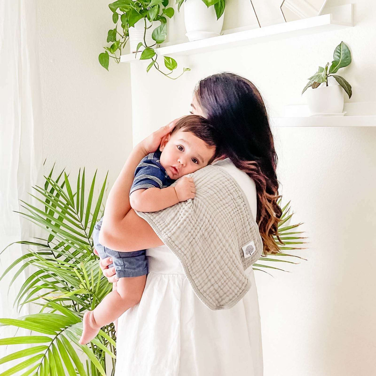 Butterfly Set - Muslin Burp Cloths (4 Pack) absorbent burp cloths for under 2, shown over a mother's shoulder while she carries her child.